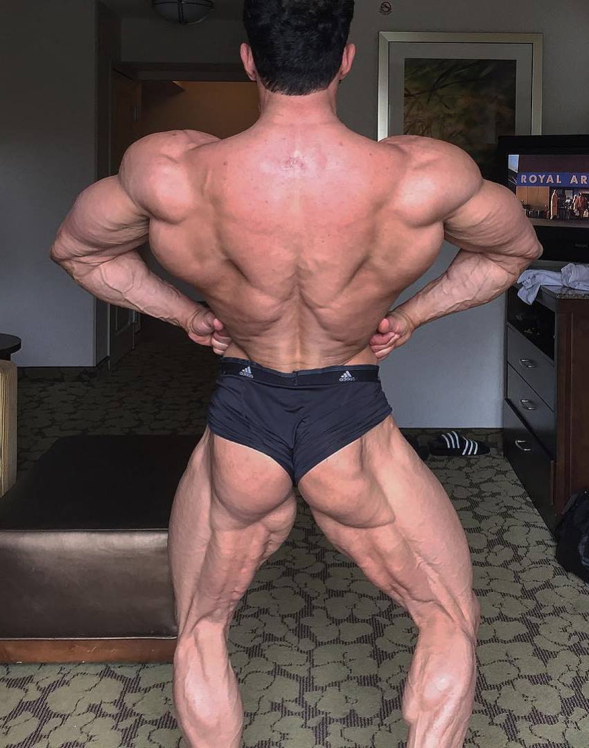 Arash Rahbar practicing rear lat spread pose at his home, looking incredibly conditioned