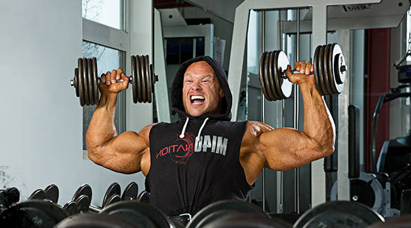 Ben Pakulski completing an overhead dumbbell raise 