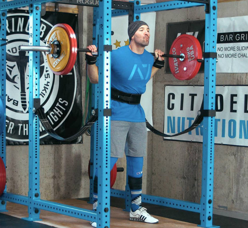 Brandon Campbell standing in squat rack, completing a squat with his large chest puffed out