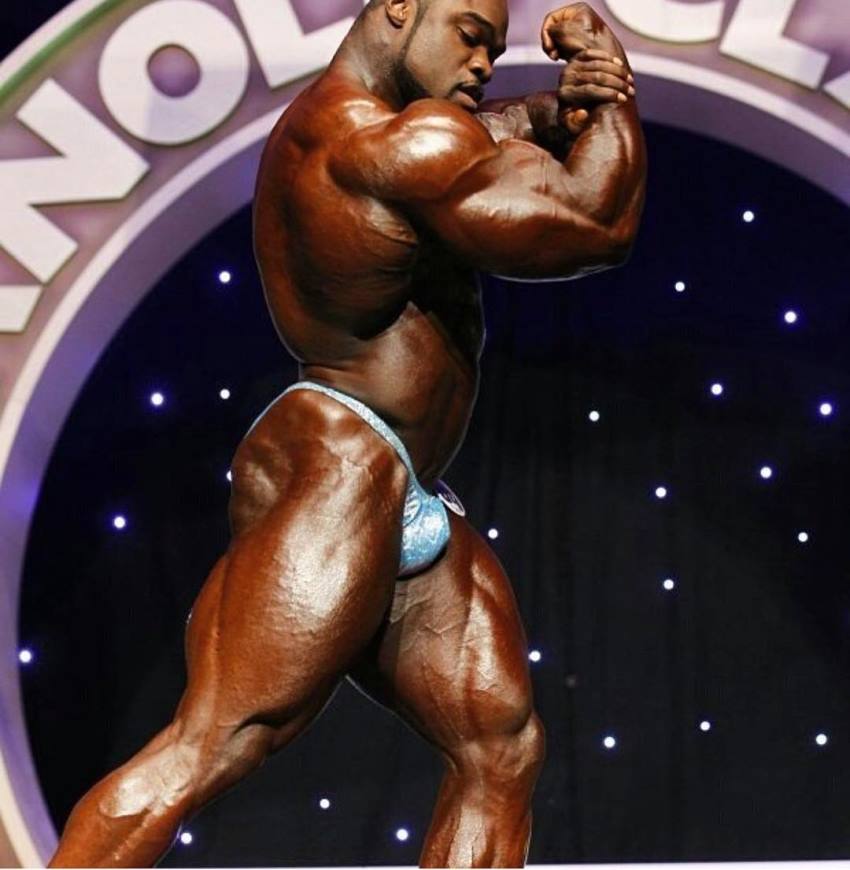 Brandon Curry doing a side pose on the Arnold Classic stage, being in top conditioning