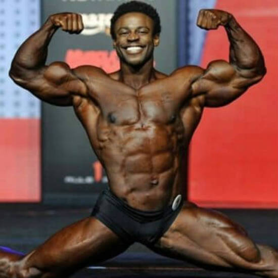 Breon Ansley completing the spllits and tensing his biceps at a competition