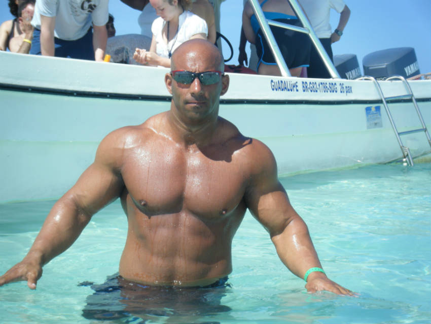 Christian Thibaudeau swimming in the sea, howing his large arms, shoulders and toned abs 