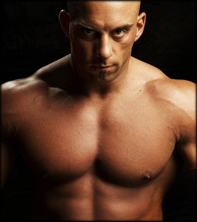 Christian Thibaudeau showing his large chest and abs in close up eye contact shot