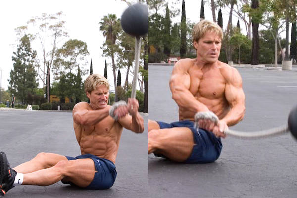 Clark Bartram completing an oblique twist with a ball on a rope, showing his abs, obliques and chest