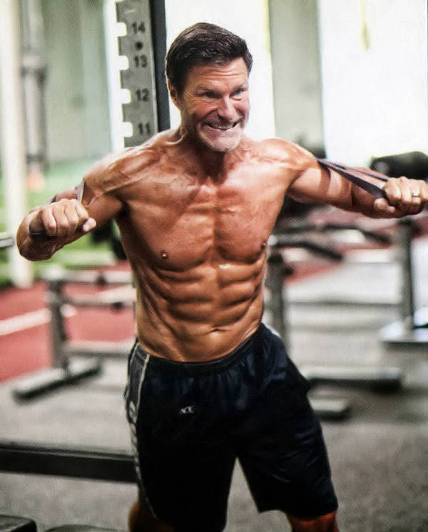 Clark Bartram using a resistance band to work his large shoulders, chest and abs