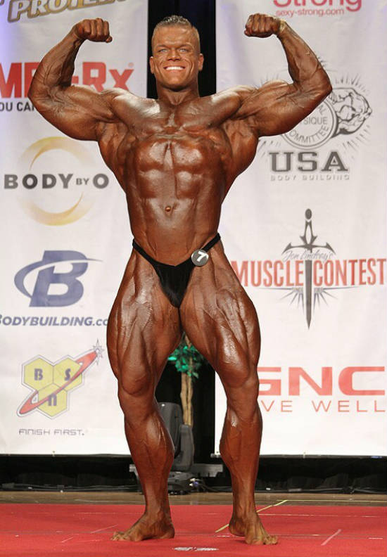 Dallas Mccarver standing in a rpoud pose at a competition, showing off his gargantuan physique