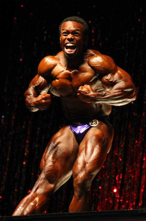 Daron Lytle beating his chest at a competition, showing off his large chest, quads and arms 