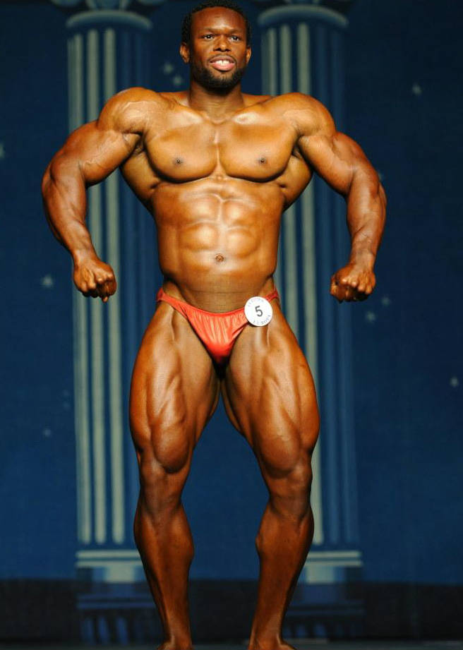 Daron Lytle posing at a competition, showing his large quads, ripped abs and toned arms