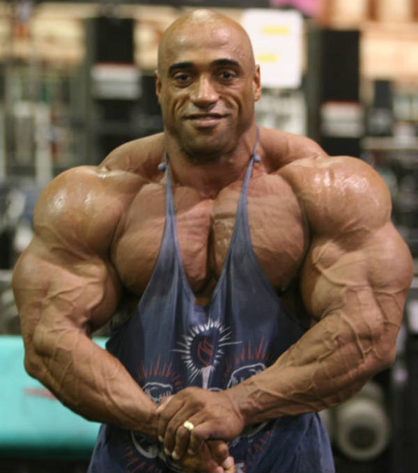 Dennis James showing his large, vascular arms and pumped chest