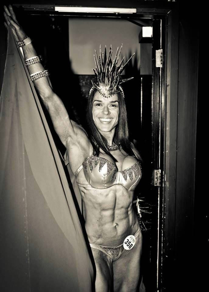 Donna De Lisser showing her ripped abdominal muscles and large arms while wearing a carnival themed outfit