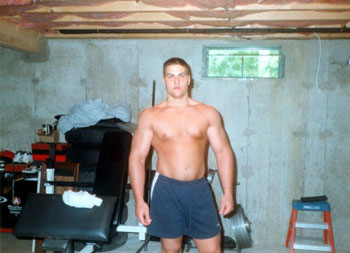 Evan Centopani as a young man showing off his large chest in his basement gym 