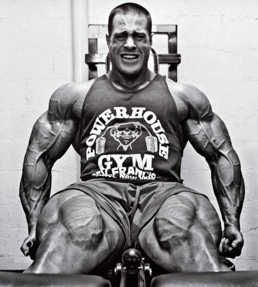 Evan Centopani completing a leg raise, showing his large vascular arms and massive quads