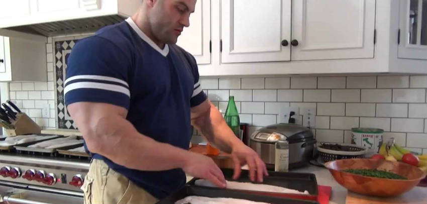 Evan Centopani prepared fish to eat at home, showing off his large arms, chest and forearms 