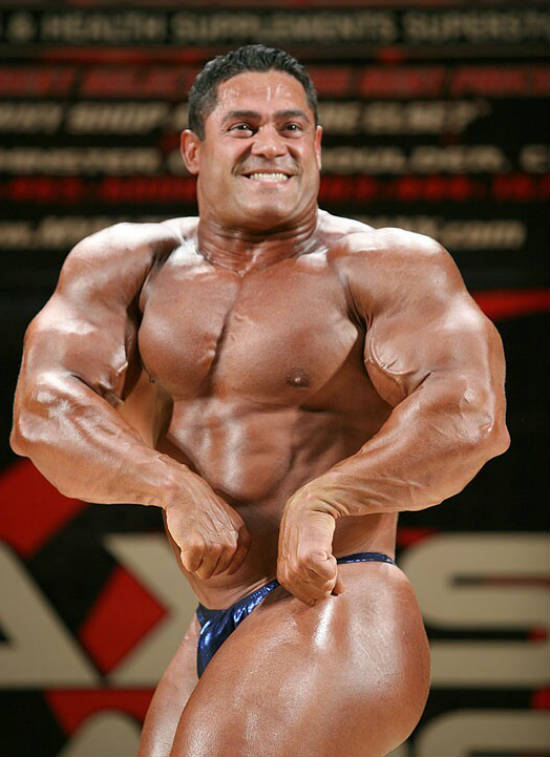 Gustavo Badell posing at a competition, showing off his large arms, bulging chest and toned abs