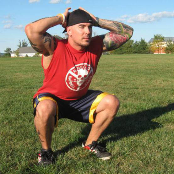 Jason Ferruggia compleing a bodyweight squats, showing his large calves and arms