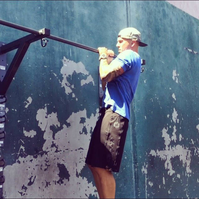 Jason Ferruggia completign a pull up on a metal bar, showing his large arms 