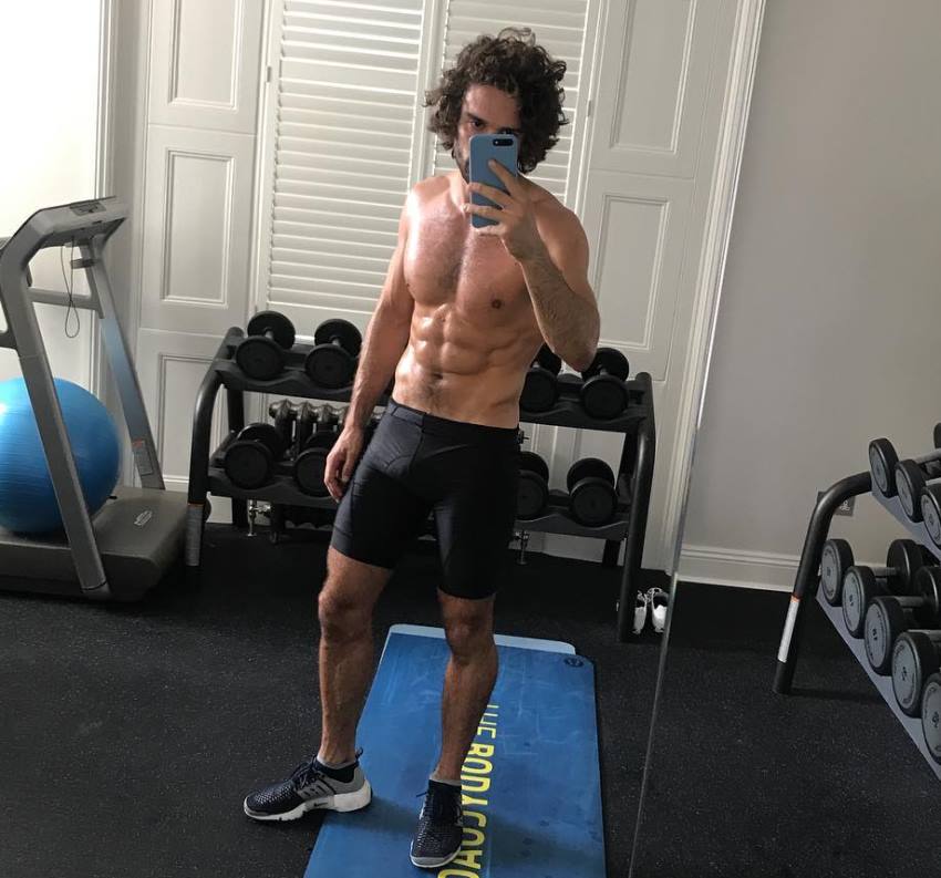 Joe Wicks taking a selfie in a gym, showing off his fit upper body