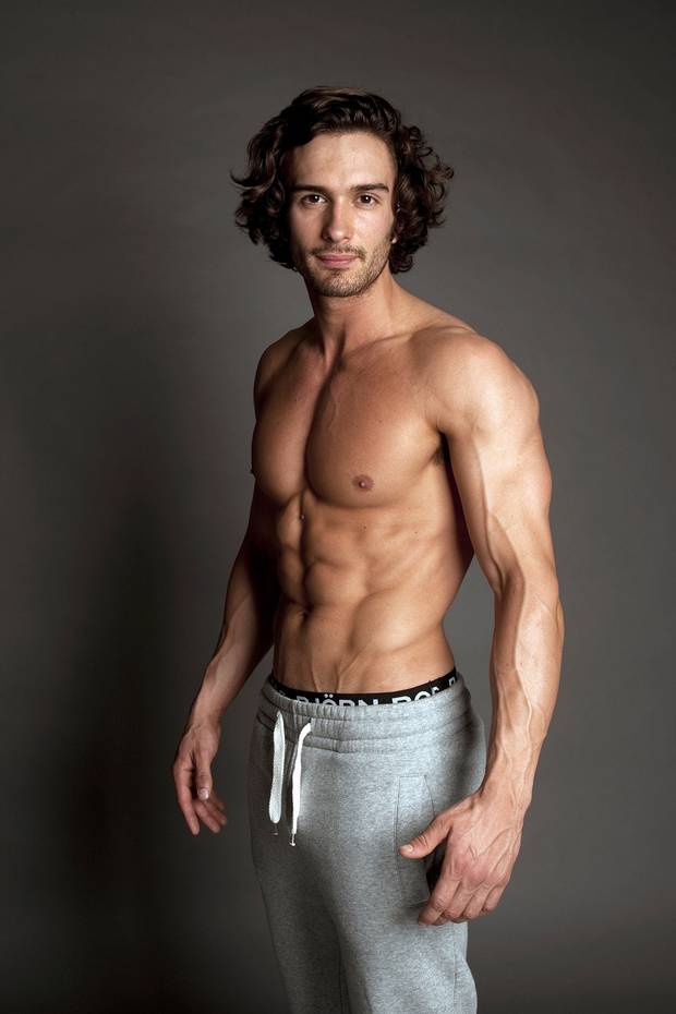 Joe Wicks shirtless in grey track pants, displaying his muscular arms, chest, and abs