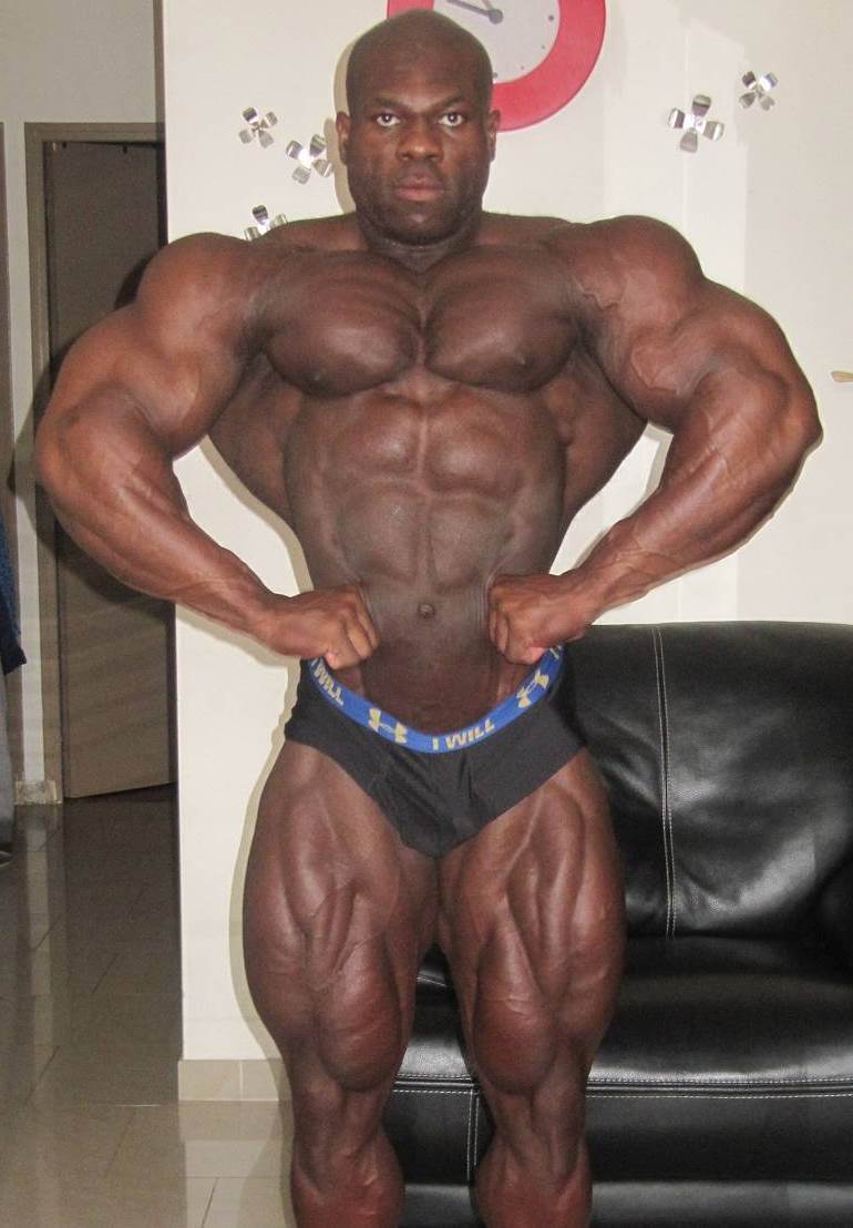 Lionel Beyeke doing a front lat spread in his room, practicing for a contest, while showing his impressive conditioning