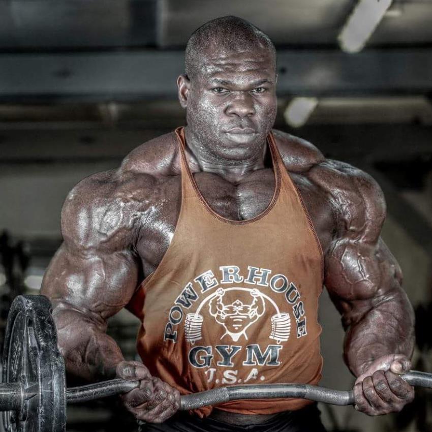 Lionel Beyeke doing barbell biceps curls with his strong, and big arms