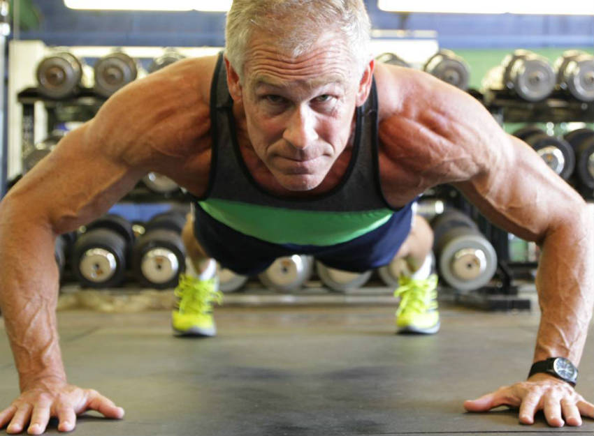 Mark Mcilyar completing a pressup, showing his toned delts, vascular arms and large biceps