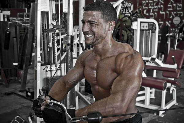 Matt Acton completing a chest flye on the cable machine, showing his pumped chest and arms