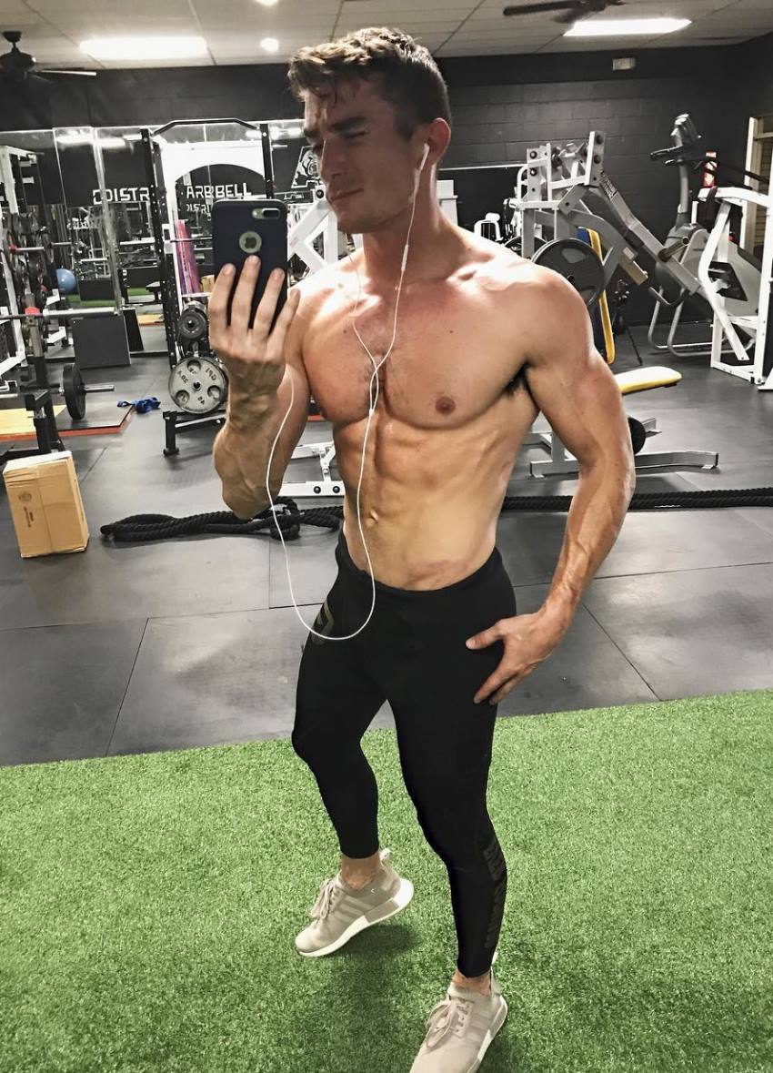 Maxx Chewning taking a shirtless selfie in the gym, showing his strong and muscular upper body