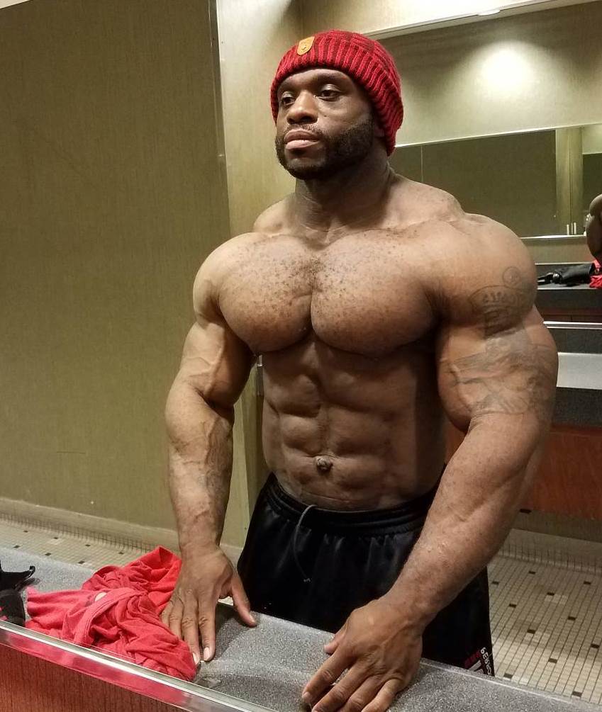 Michael Lockett standing in front of a mirror, looking at his sculpted physique