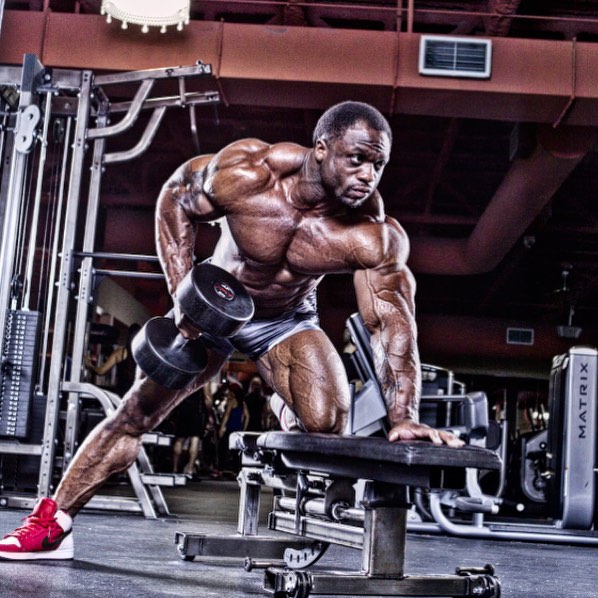 Michael Lockett doing single-arm bent over rows in the gym, looking ripped