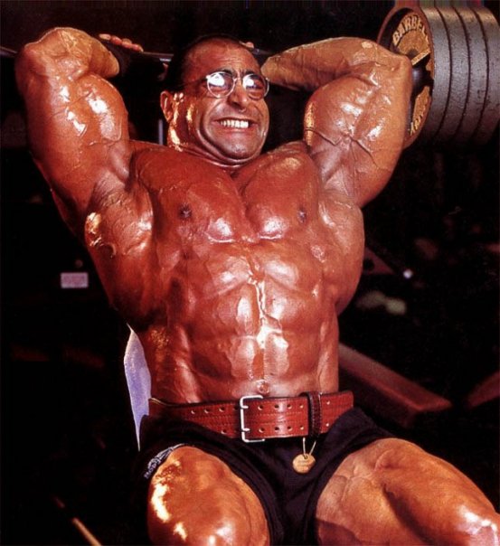 Nasser El Sonbaty completing a tricep extension, showing his bulging triceps and large abdominal muscles