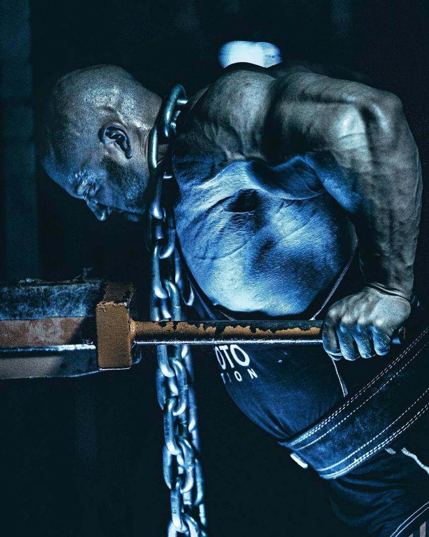 Petar Klancir doing dips with chains around his neck, his arms looking enormous and defined