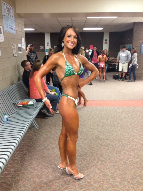 Rachel Morrissey standing backstage at a competition, showing her tanned up ans, quads and arms
