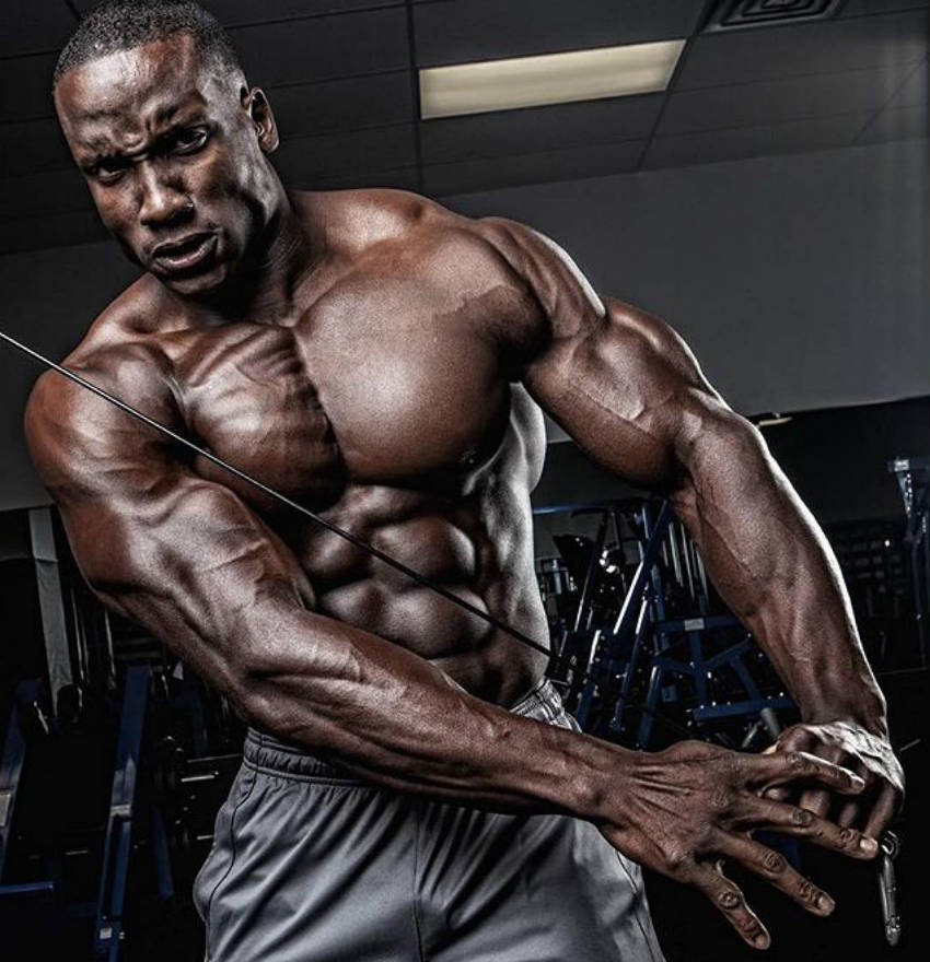 Robert Timms completing a cable crossover, showing his large chest, ripped abs and huge arms