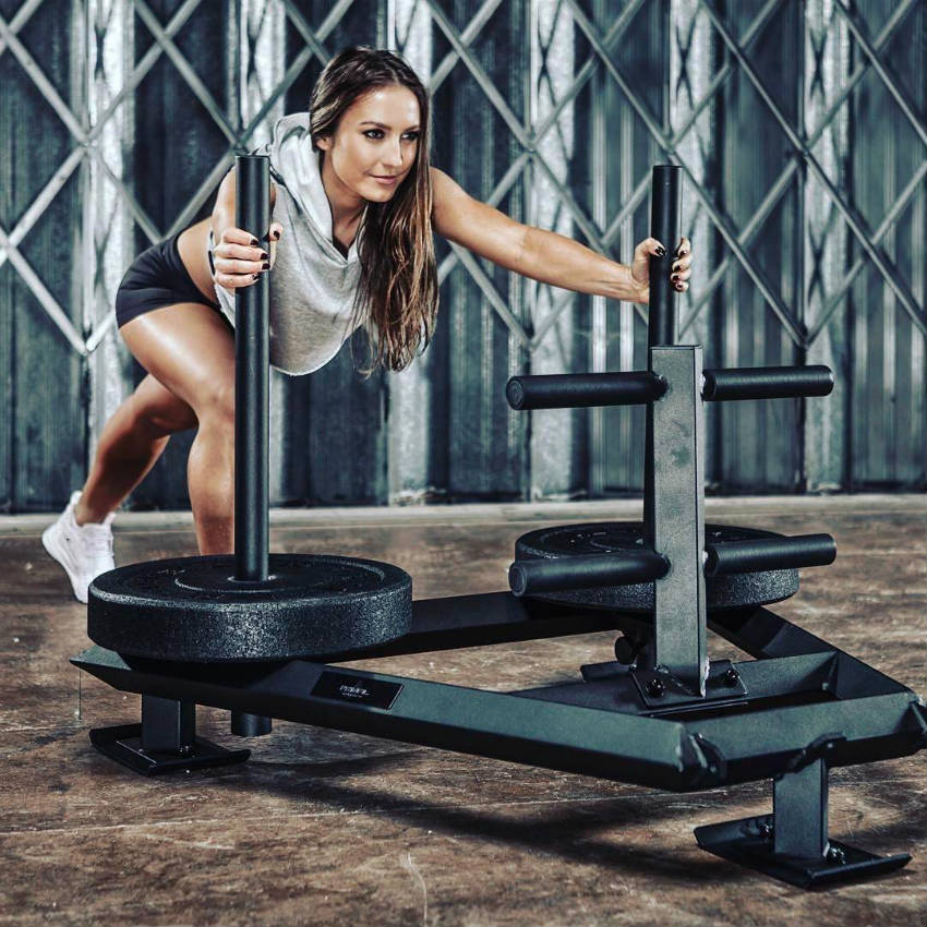 Sandra Radav pushing a sled with weights, showing her arms and legs