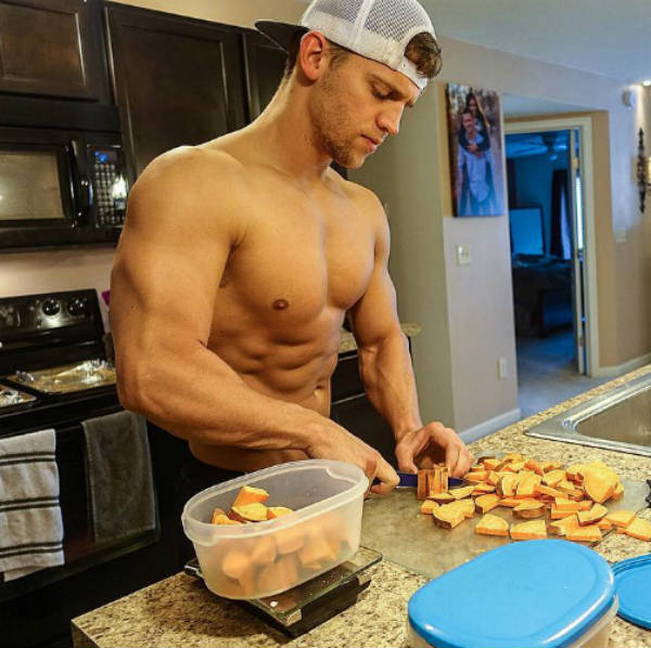 Tyler Stines preparing sweet potatoes, showing off his large tricep, chest and ripped abs