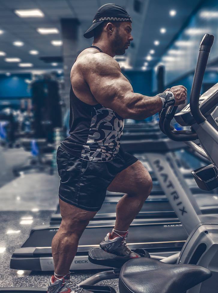 Babak Akbarniya on a treadmill machine, his arms looking massive and aesthetic from the side