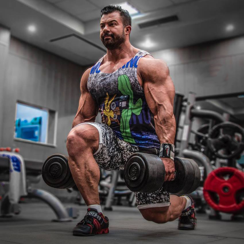 Babak Akbarniya doing lunges, his arms, shoulders, and calves looking big and ripped