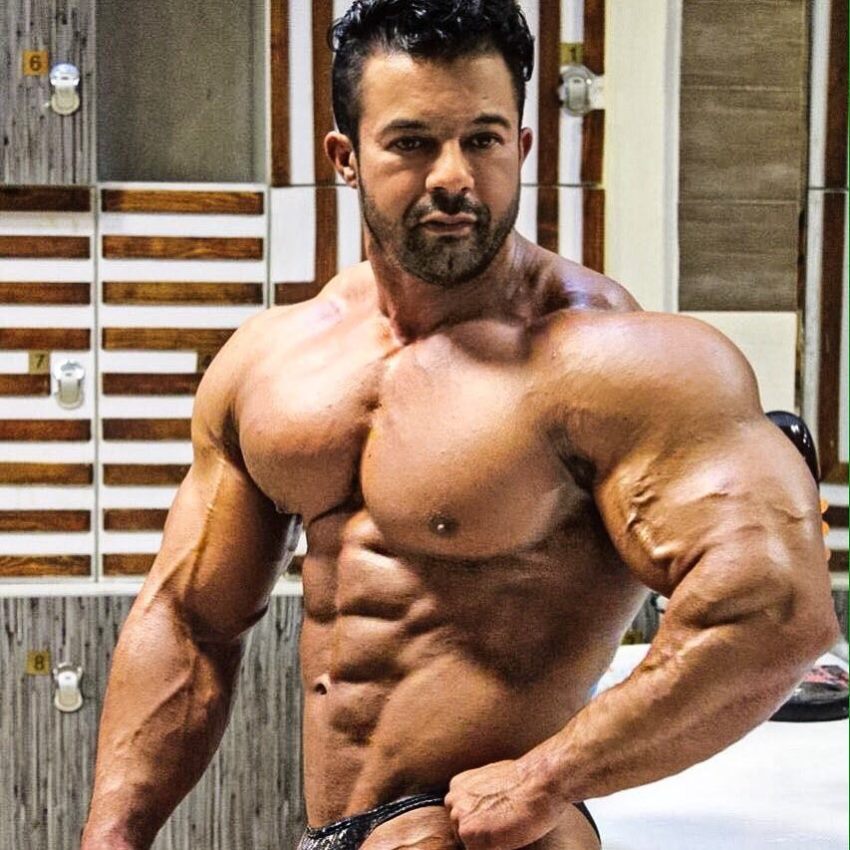 Babak Akbarniya doing a shirtless side pose, looking massive and aesthetic