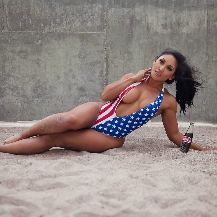 Genevieve Ava laying on the beach in a US flag bikini, showing her toned figure