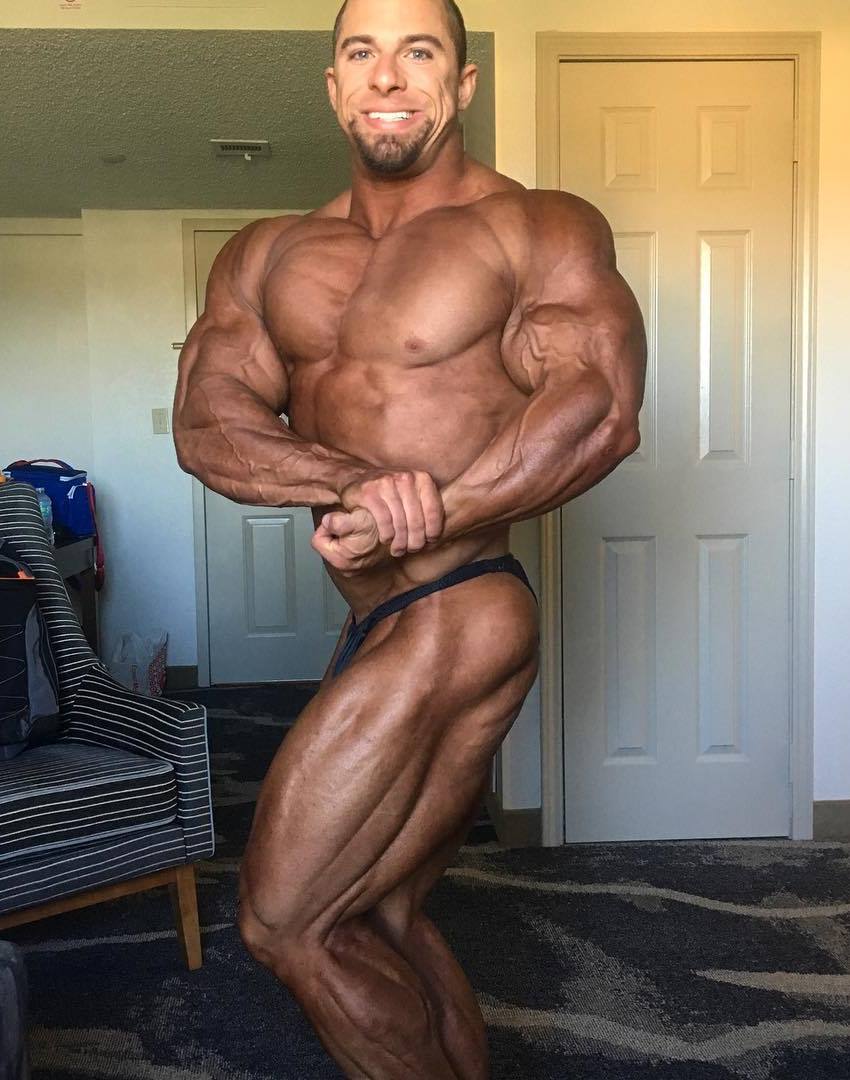 John Jewett is a side chest pose, tanned up, showing his ripped and muscular physique