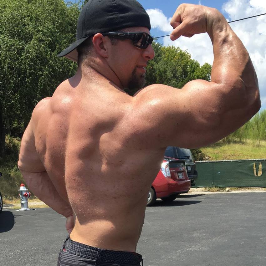 John Jewett flexing his massive biceps and back on an outdoor parking lot