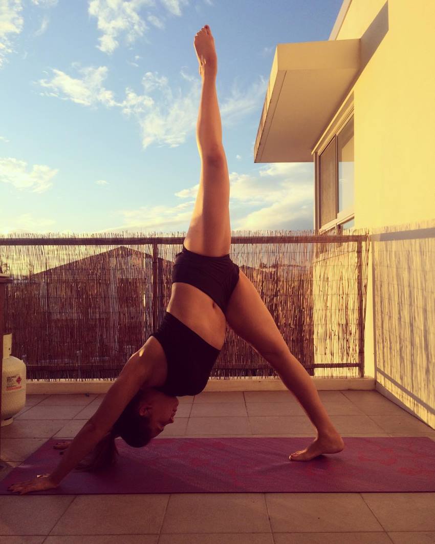 Lauryn Clare doing stretches on a pink mat on her balcony, looking fit and awesome
