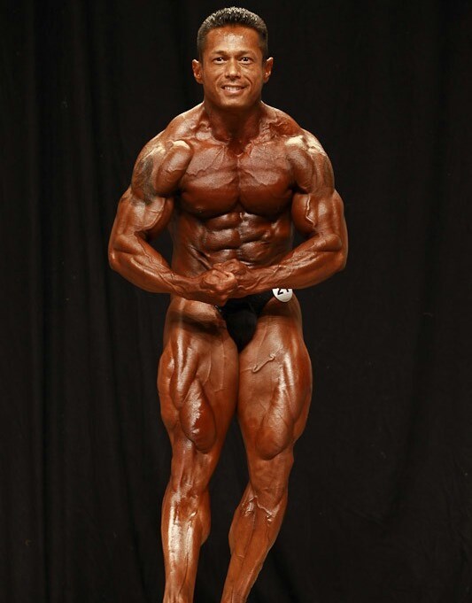 Leonardo Pacheco in a most muscular pose on the stage, showing his ripped physique to the audience