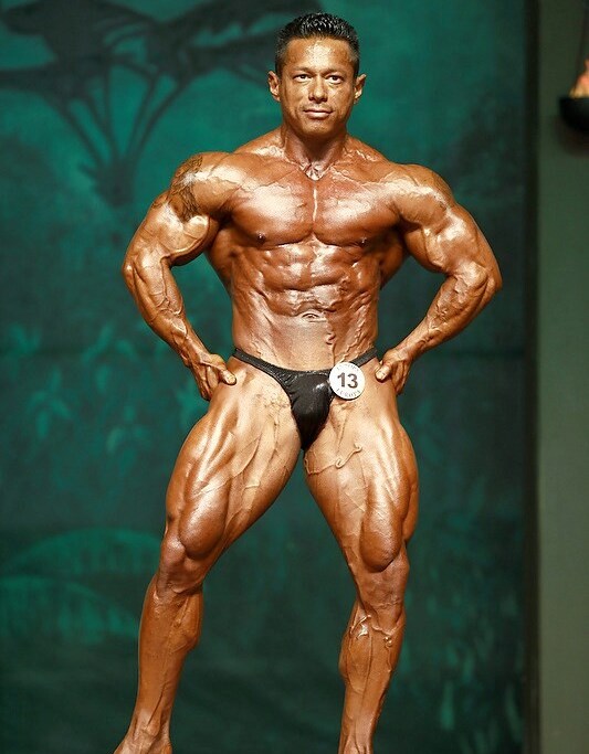 Leonardo Pacheco flexing his muscles and showing the to the judges on the bodybuilding stage