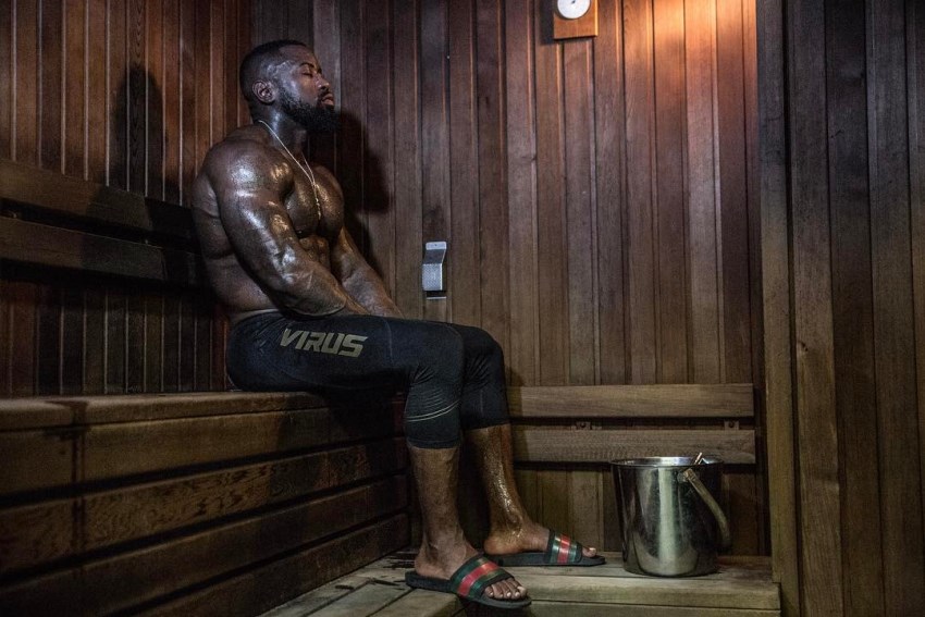 Mike Rashid sitting in a hot sauna, his ripped body being covered in sweat