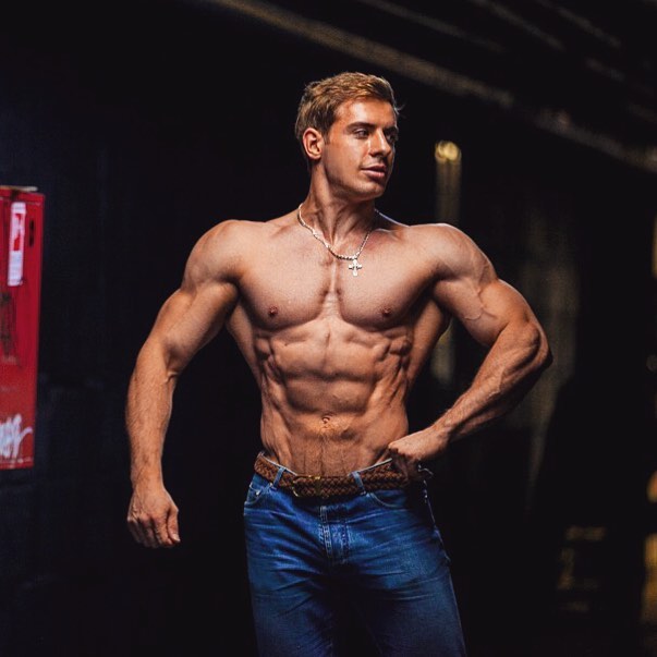 Nikolay Kuleshov standing shirtless in jeans, posing and showing his ripped and muscular body