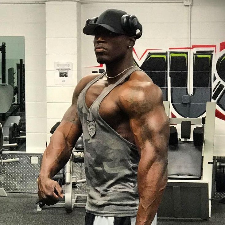 Otto Montgomery flexing his big and ripped arms in grey tank top