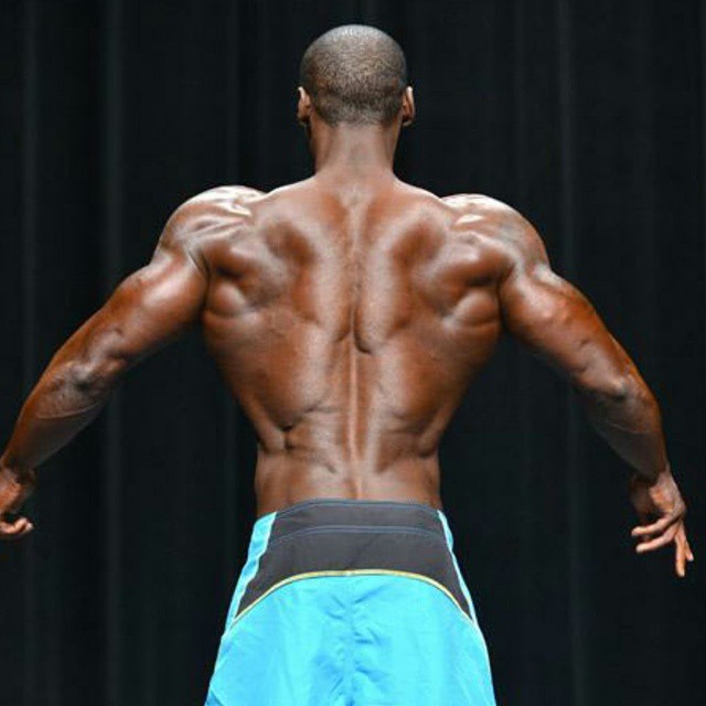 Otto Montgomery spreading his lats on the stage, showing his muscular and aesthetic back to the judges
