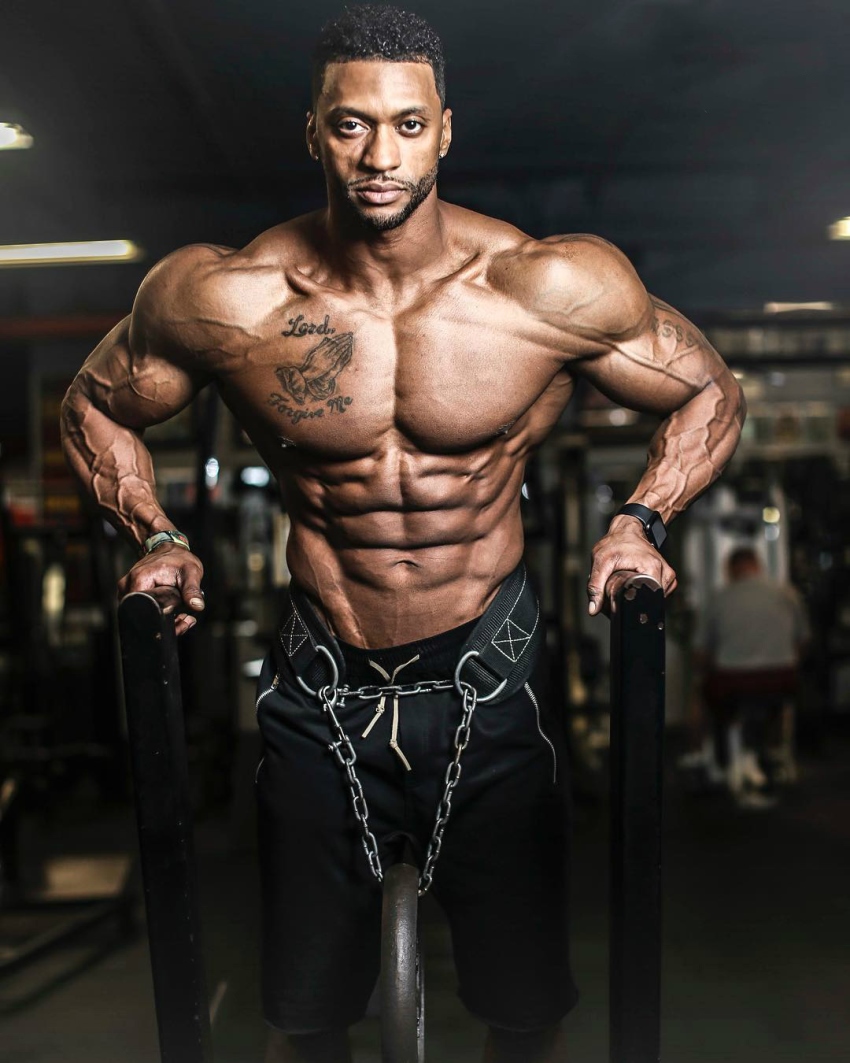 Shirtless Raymont Edmonds doing dips as he looks straight into the camera