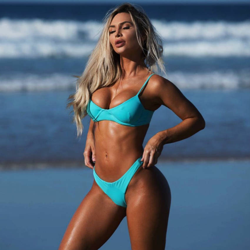 Rosanna Arkle standing on a bach, showing her toned abs, legs and arms